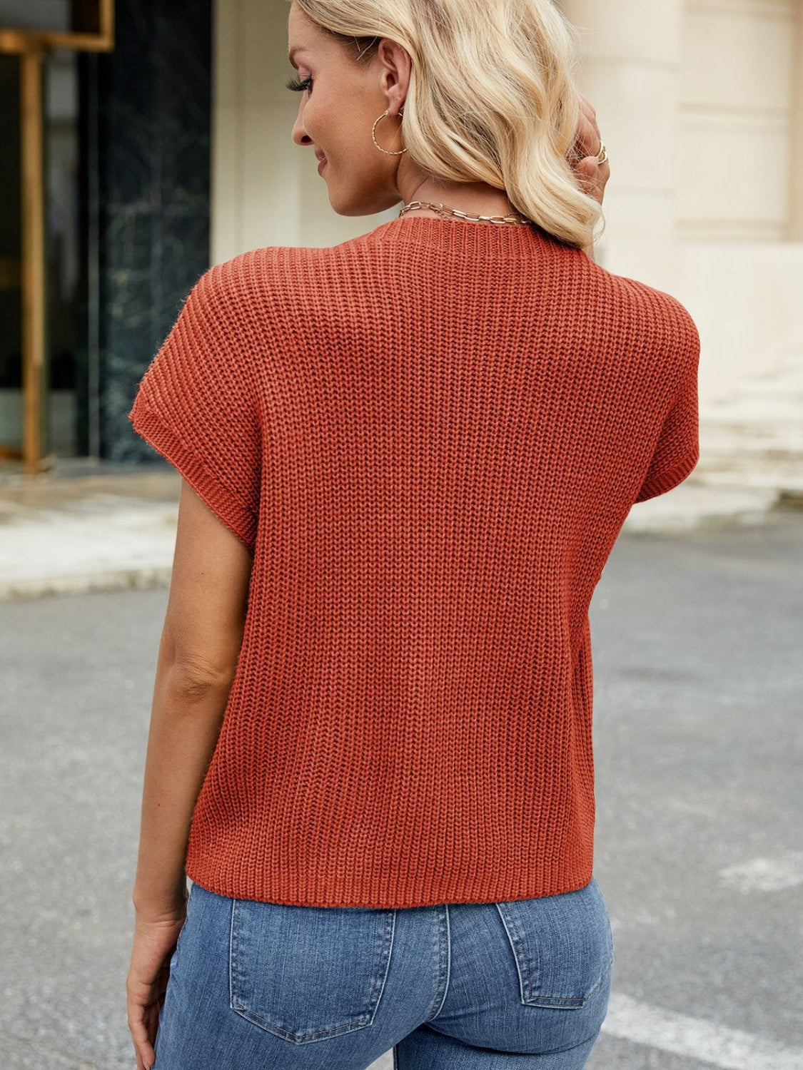 Knit cap-sleeve top in rust orange with ribbed texture and a mock neckline.