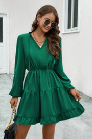 Green tiered ruffle sleeve mini dress with tie neck and smocked waist.