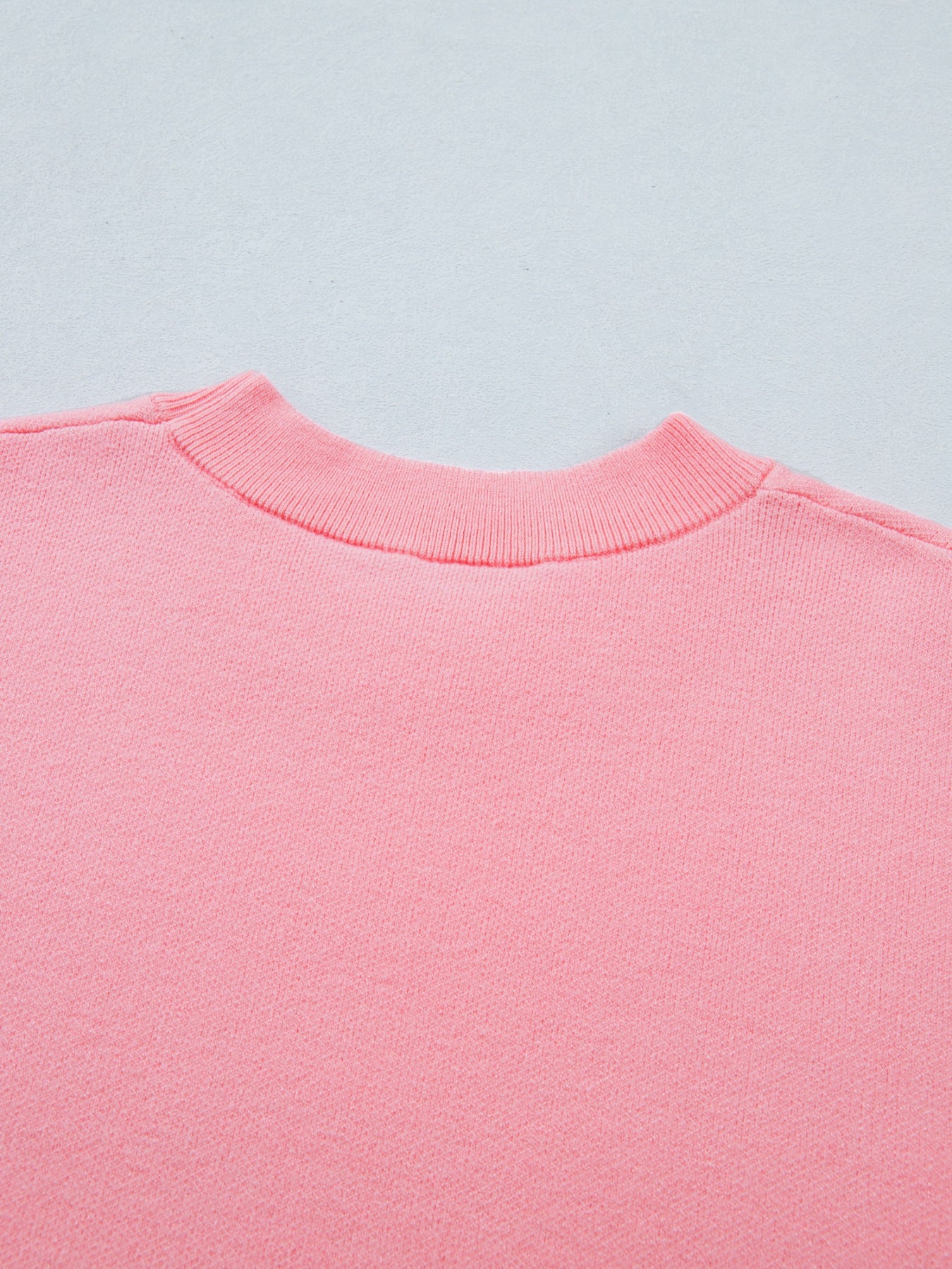 Pink knit top with ribbed mock neck and scalloped hem detail.