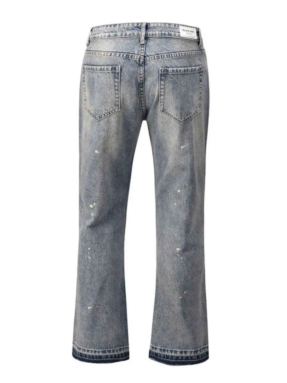 Distressed wash bootcut jeans with raw hem and paint splatters.
