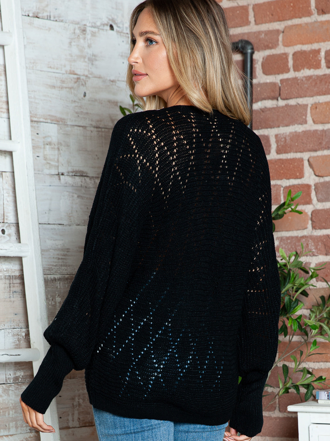 Black acrylic dolman sweater with openwork lace trim and wide sleeves.