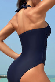 Dark blue halter swimsuit with crossover front and mesh insets on the side.