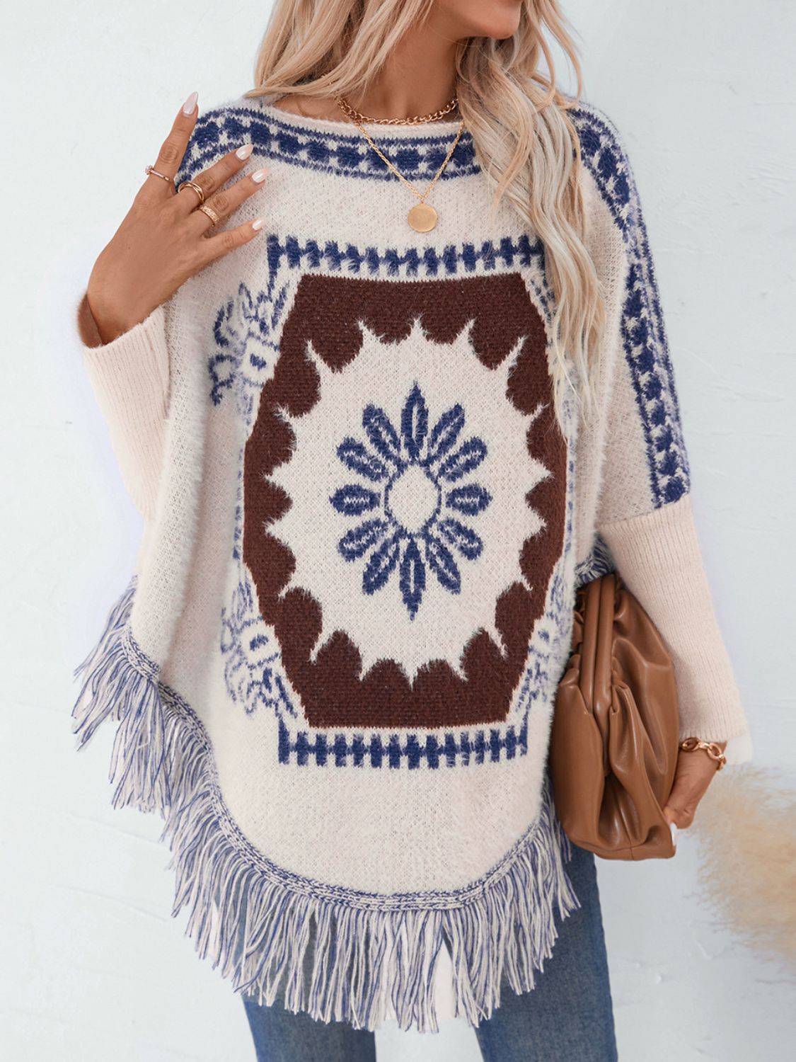 Cream acrylic poncho with Aztec motif, fringe hem, and boat neck.