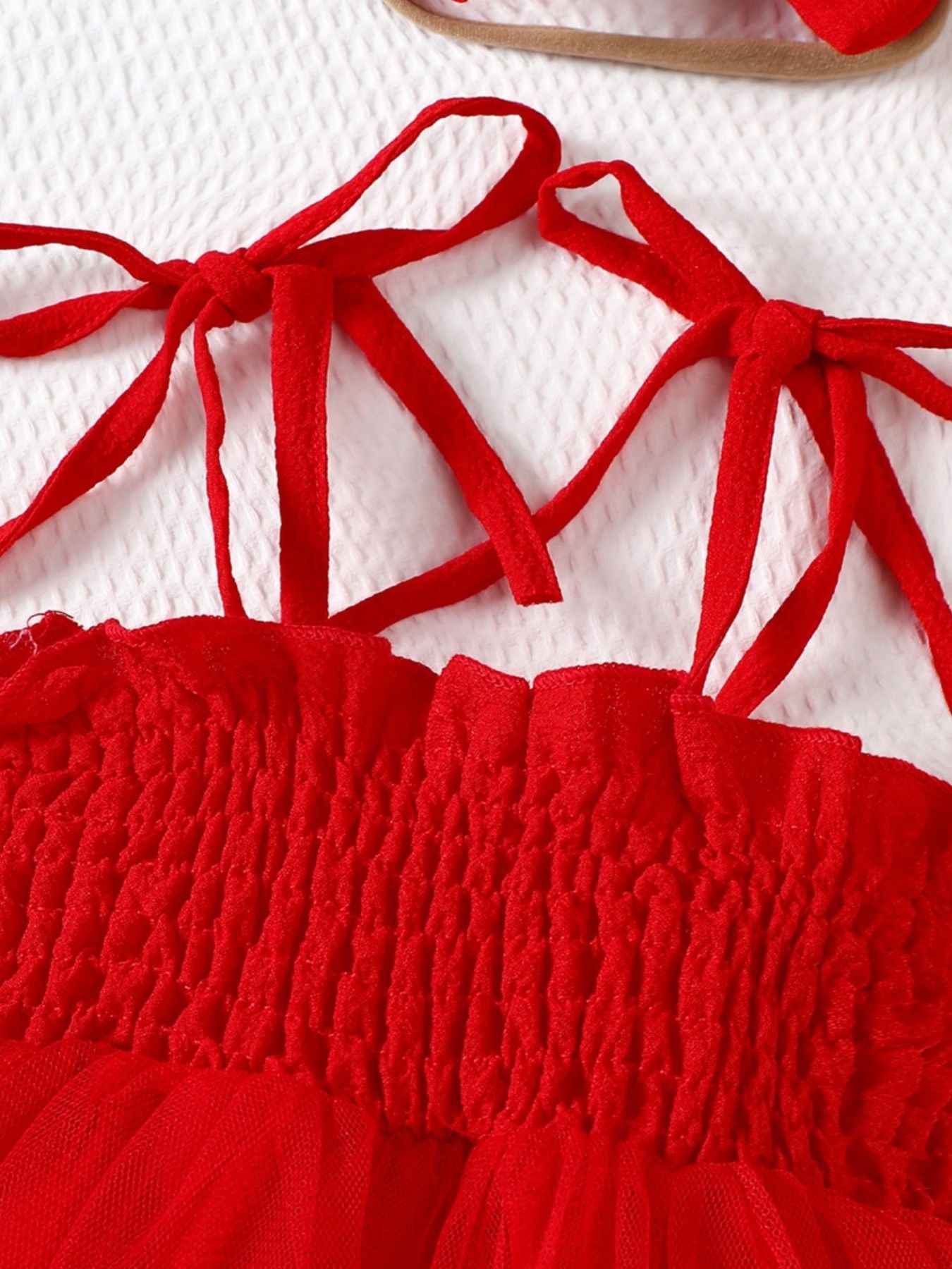 Red smocked bodysuit dress with tie straps and tulle skirt detail.
