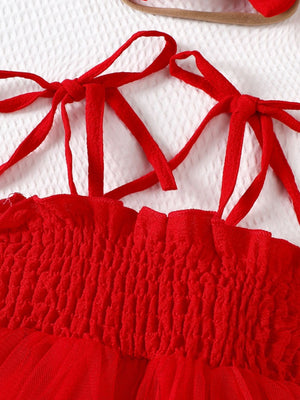 Red smocked bodysuit dress with tie straps and tulle skirt detail.
