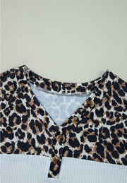 Leopard print henley sweater with button detail and waffle knit bottom in white.
