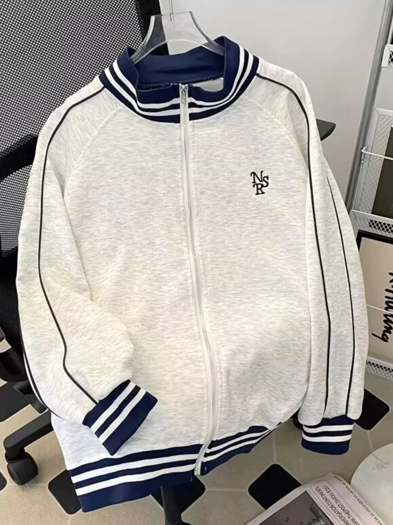 Gray zip-up sweatshirt with navy blue striped collar and cuffs, featuring side stripe detail.