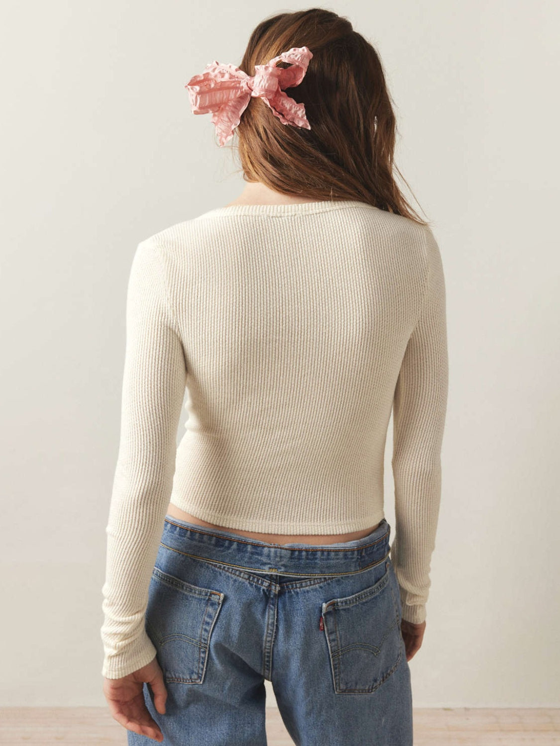 Cream ribbed long sleeve crop top with a crew neck, styled with jeans.