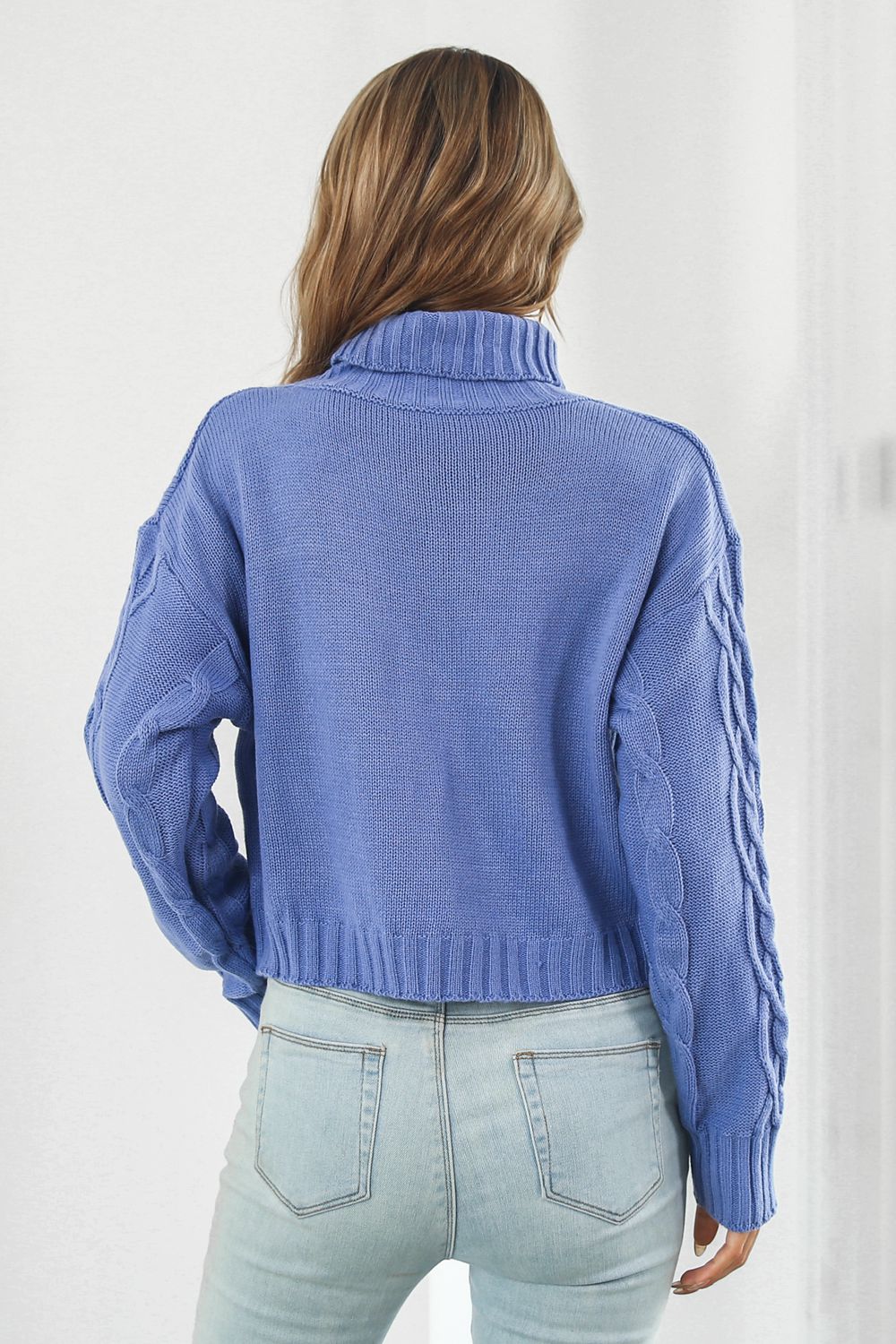 Blue acrylic cable knit cropped turtleneck sweater with braided sleeves.