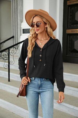 Black textured henley hooded knit top with button placket and drawstring.
