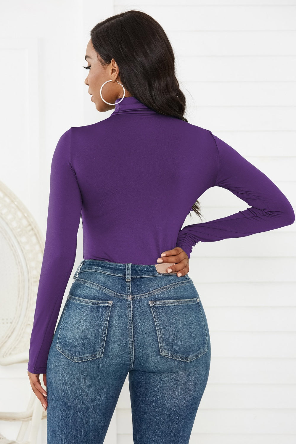 Purple turtleneck thong bodysuit with long sleeves, paired with blue jeans.