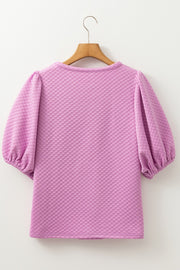 Textured quilted puff sleeve blouse in pink purple with a round neckline.