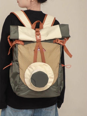 Roll-top nylon backpack in moss, cream, and tan with orange accents and a circular front pocket.