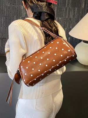 Brown polka dot shoulder bag with adjustable strap and tassel detail.