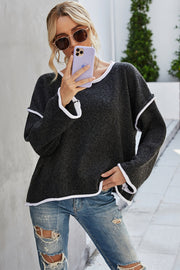 Oversized knit sweater in black with white contrast trim and frayed details.