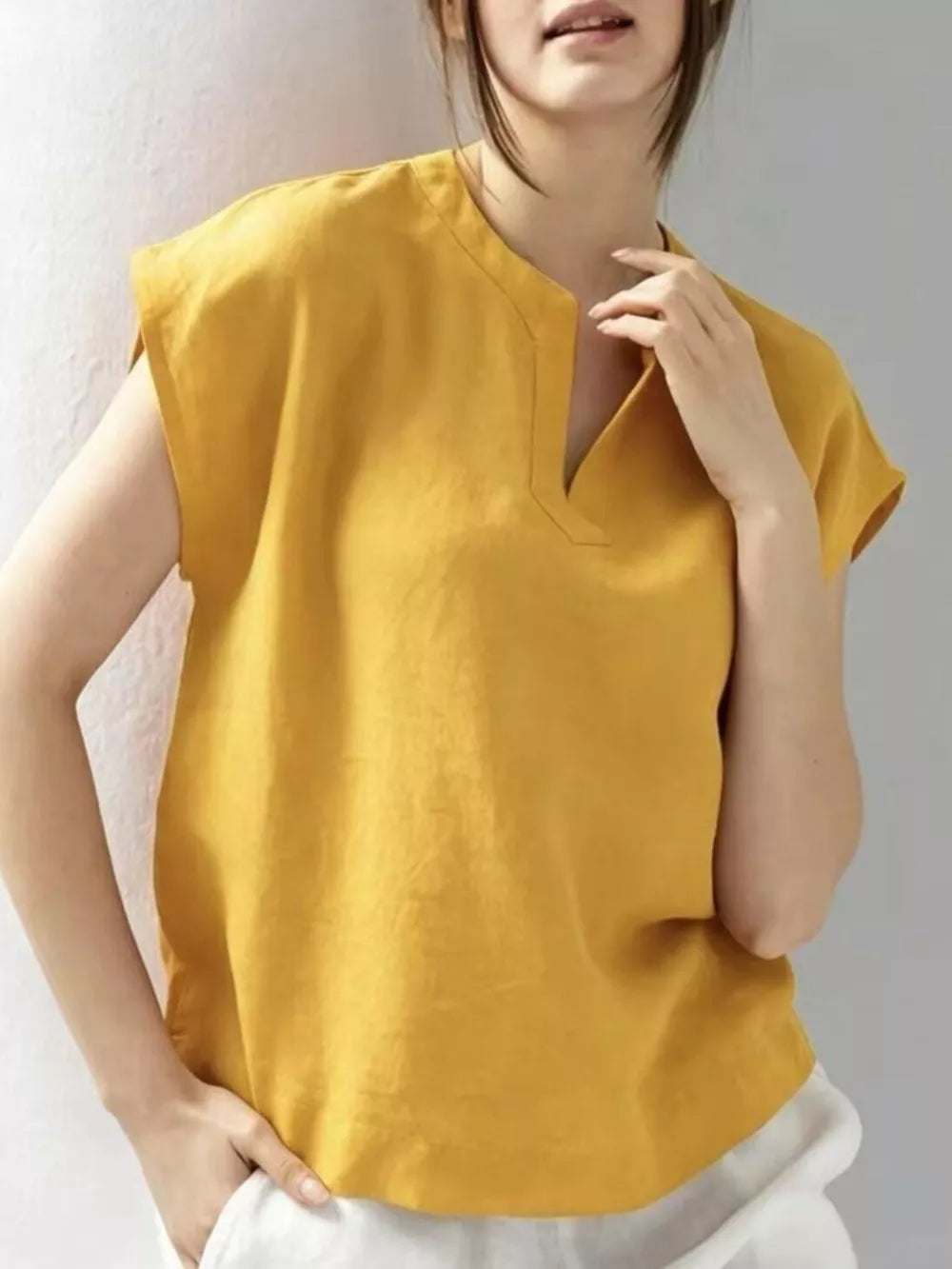 Yellow cap sleeve shirt with notched neckline and relaxed fit.