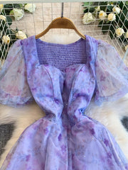 Purple floral maxi dress with sweetheart neckline, smocked bodice, and sheer puff sleeves.
