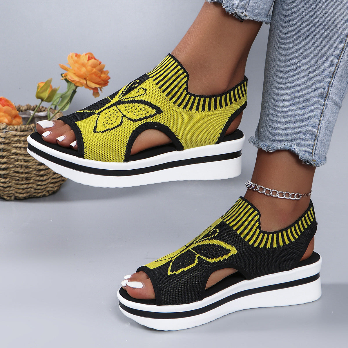 Yellow and black open-toe wedge sandals with butterfly motif mesh detail and chunky heel.