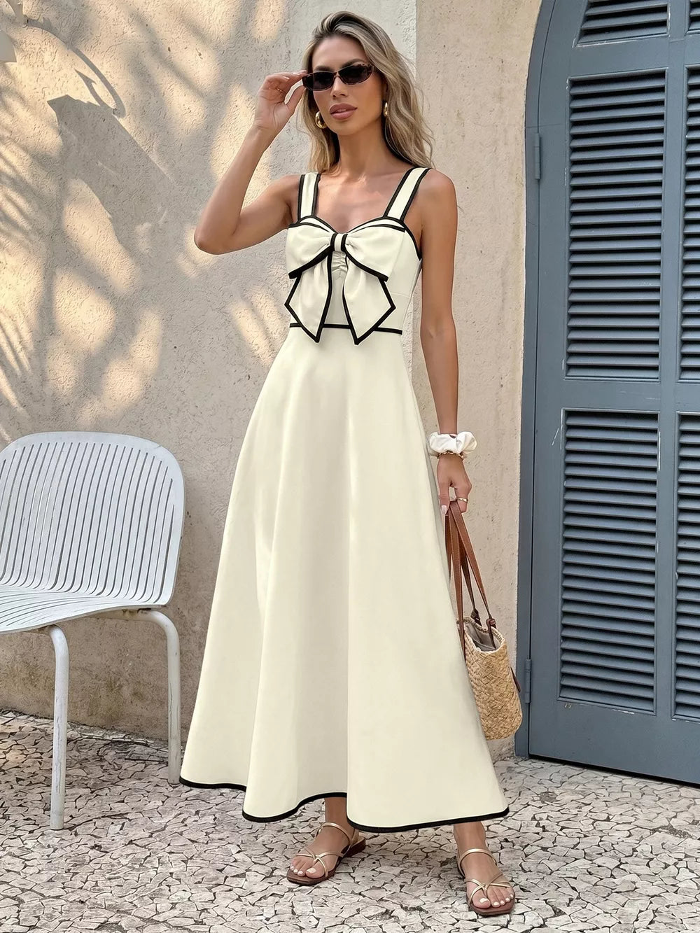 Elegant A-line midi dress in cream with black trim and a large bow detail on the bust.