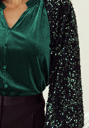 Dark green velvet blouse with sequin sleeves and ruffled collar.