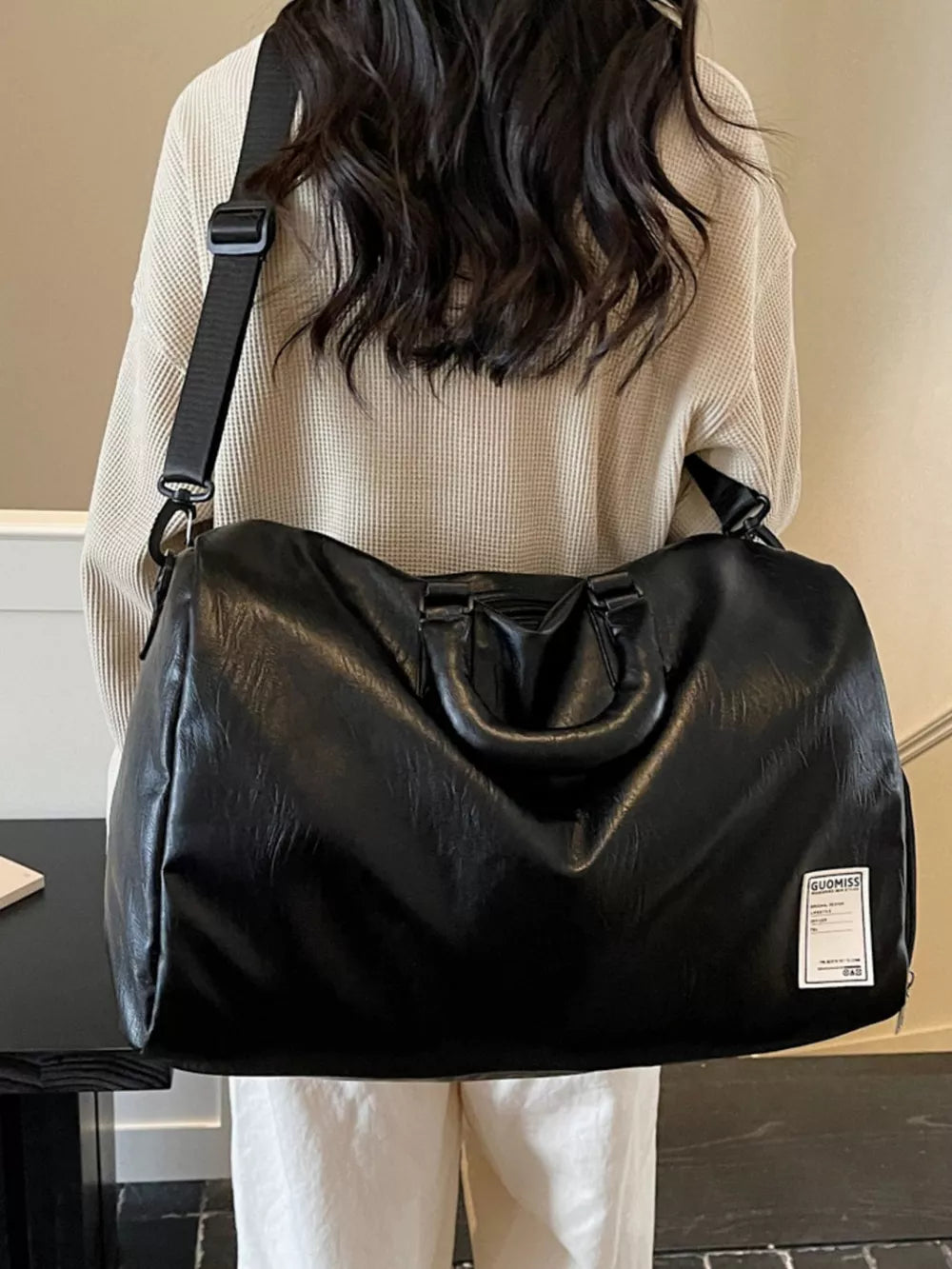Black PU leather travel bag with top handles and adjustable shoulder strap
