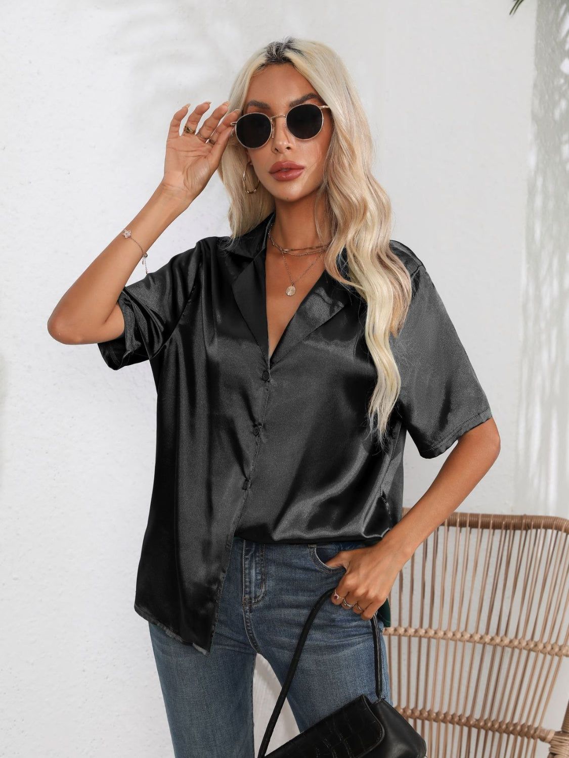 Black satin collared shirt with short sleeves and button front, styled with jeans.