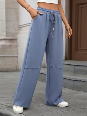 Blue high-waist drawstring wide-leg pants with pockets and a relaxed fit.