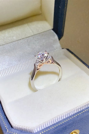 Silver moissanite trilogy engagement ring with sculpted band detail.