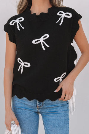 Black knit vest with white bow print, scalloped hem, and ruffled neckline.