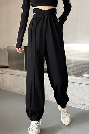 Black joggers with pleated waistline and cinched ankles, styled with a cutout top.