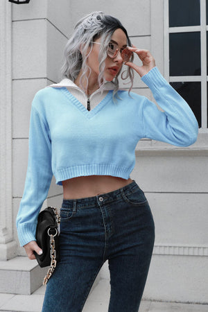 Light blue cropped acrylic sweater with zip detail and white collar, V-neck, long sleeves.