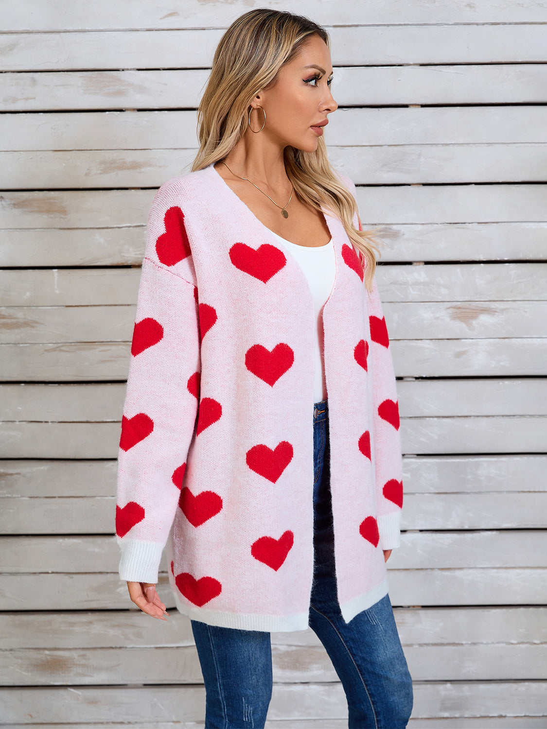 Pink acrylic cardigan with red heart intarsia pattern, open front, long sleeves.
