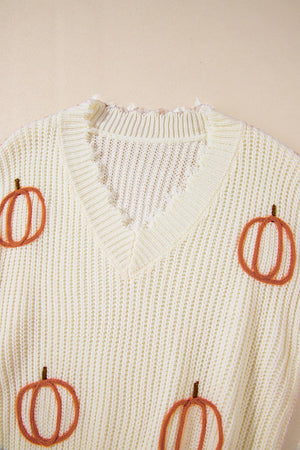 Beige distressed knit sweater with embroidered pumpkins, V-neck, and frayed trim.