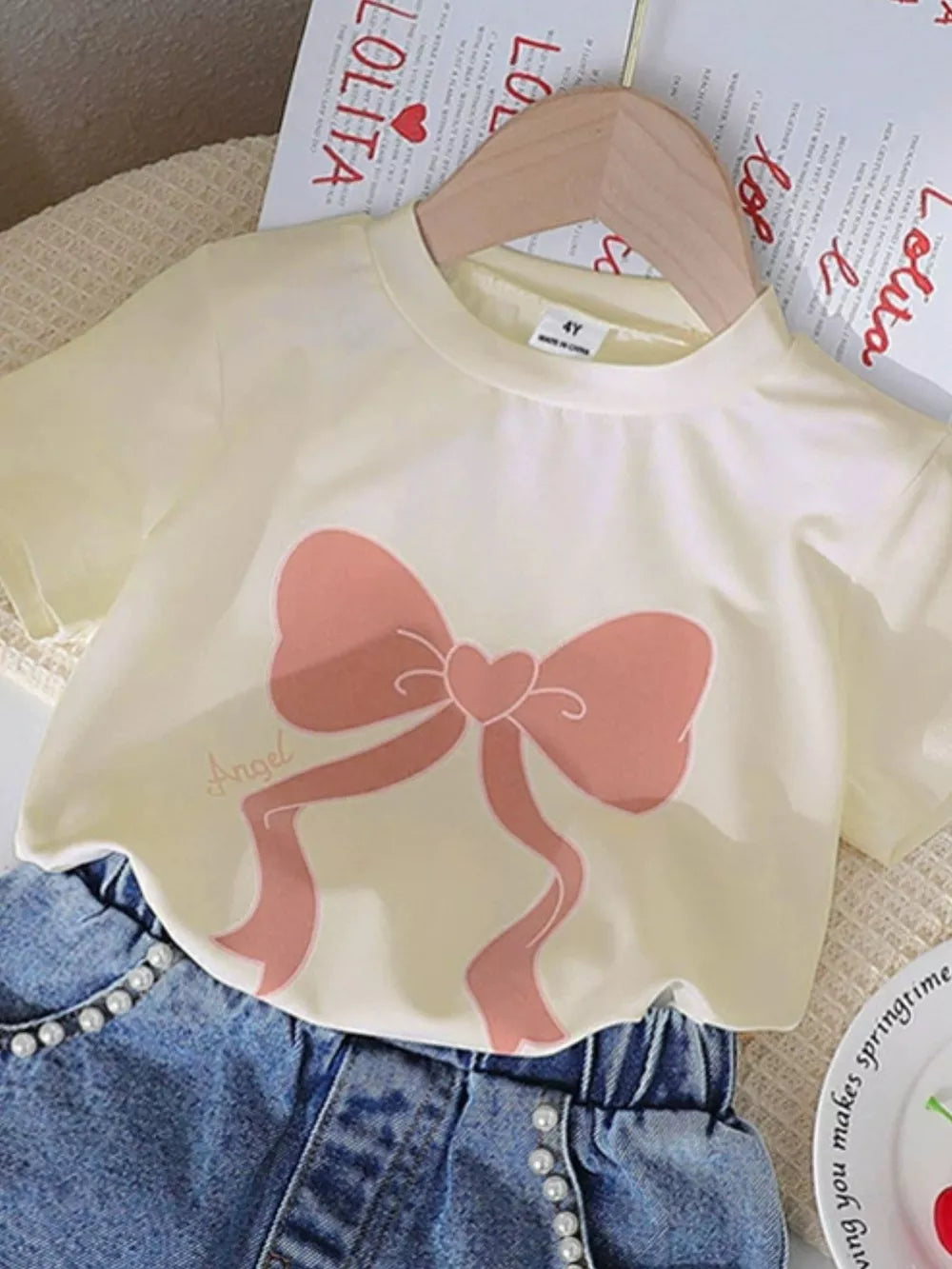 Beige tee with pink bowknot graphic and pearl-embellished denim shorts
