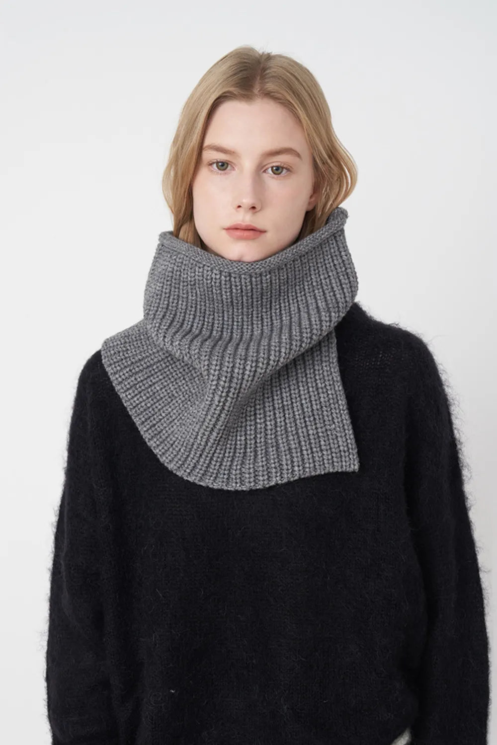 Ribbed neck warmer in dark gray with extended panel, worn over a black sweater.