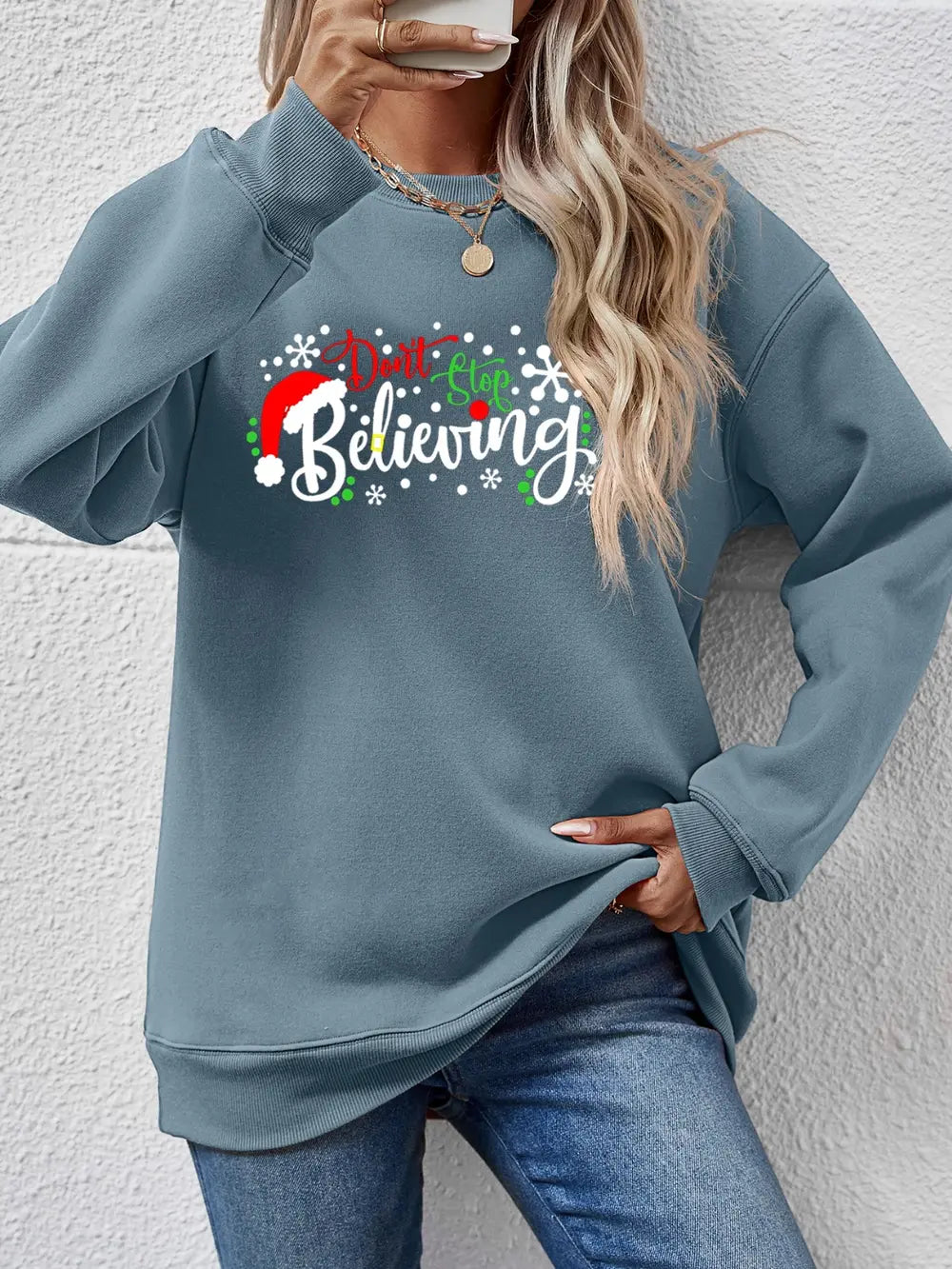 Air Force Blue long sleeve sweater with "Don't Stop Believing" graphic and Santa hat detail.