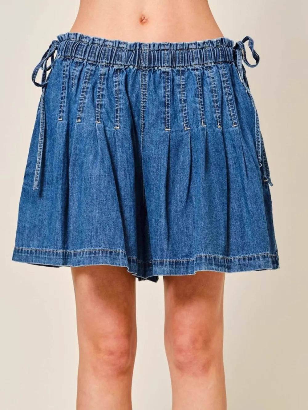 Medium blue denim shorts with ruched waist and drawstring ties.