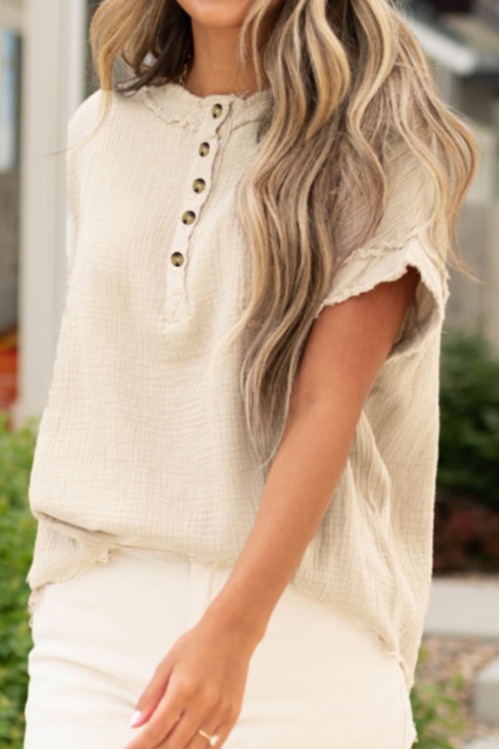 Beige textured gauze henley blouse with raw edges and button placket.
