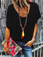 Black V-neck dolman sleeve tee with colorful beaded necklace and floral clutch.