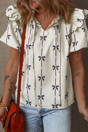 Ivory bow print blouse with ruffled sleeves and tie neck.