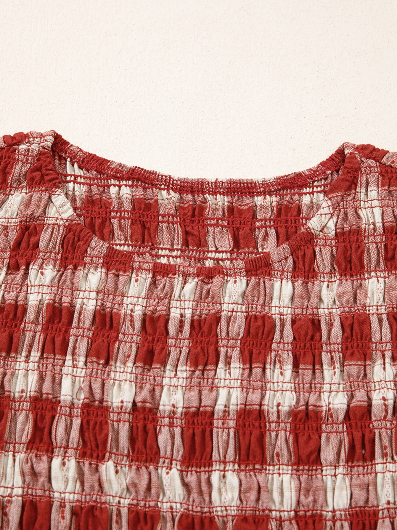 Red and white gingham smocked mini dress with a scoop neck and puff sleeves.