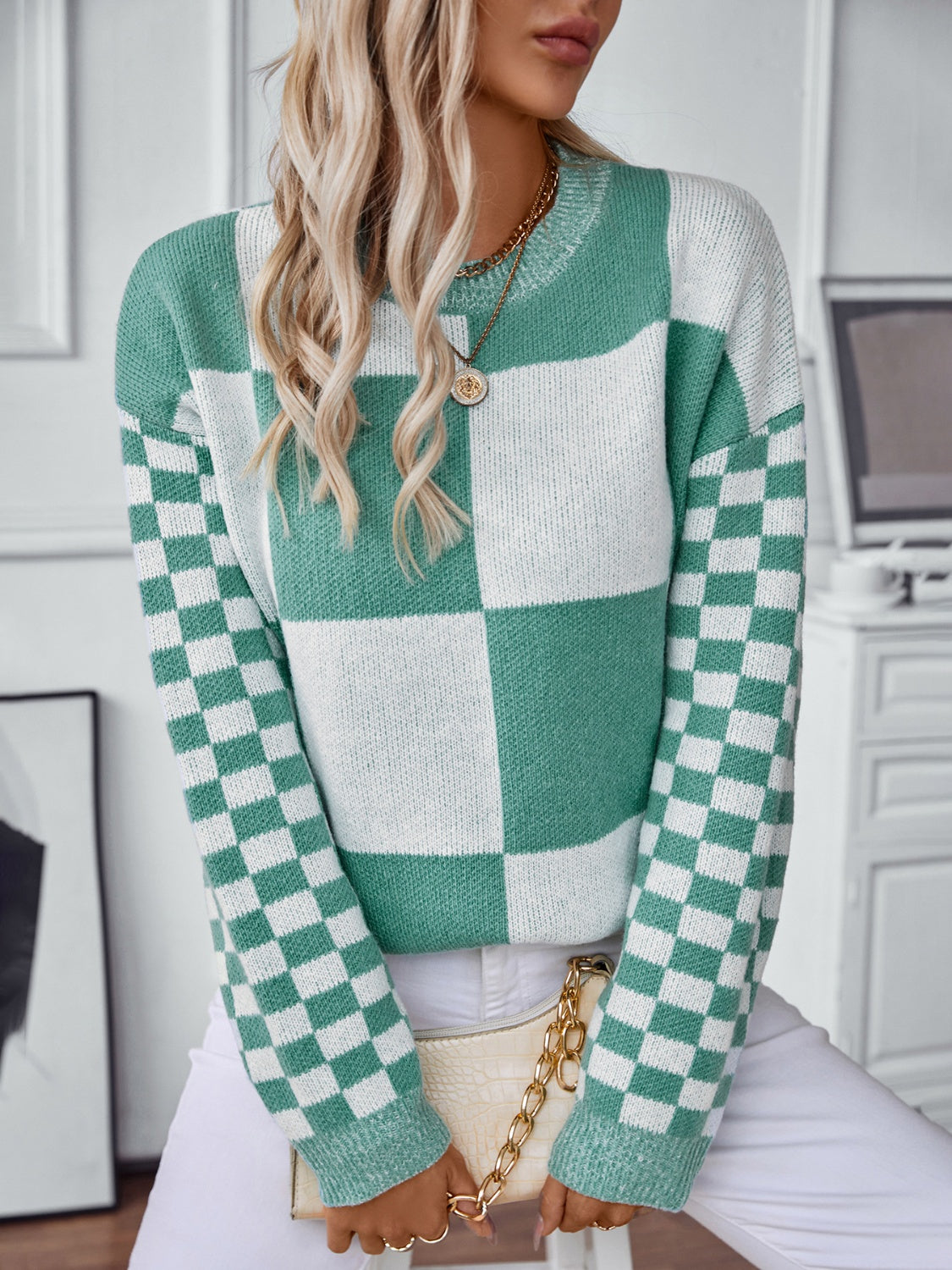 Checkerboard knit sweater in turquoise and white with a crew neck and long sleeves.