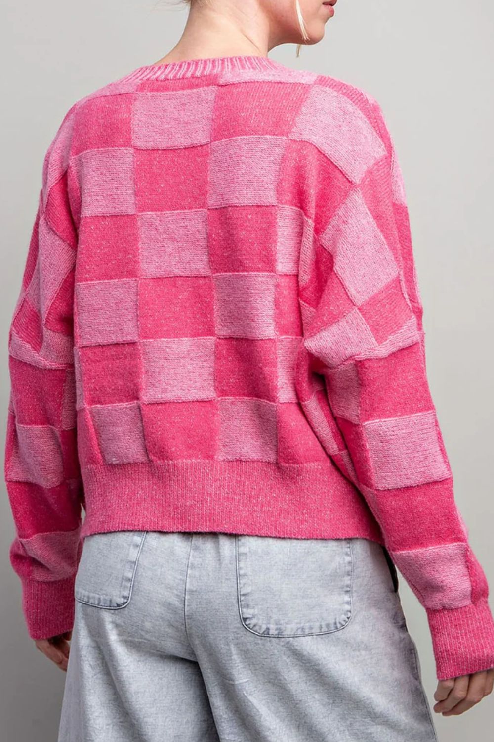 Pink checkerboard knit cardigan with crew neck and long sleeves.