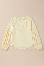 Pastel yellow blouse with gathered neckline and voluminous poet sleeves.