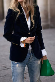 Navy velvet blazer with gold button detail and notched lapel, worn open over a white shirt.