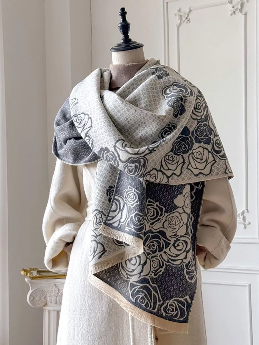 Elegant floral pattern scarf in gray and white with fringe detail.