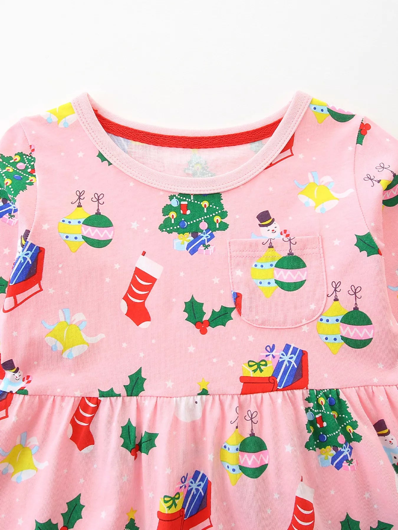 Pink long-sleeve baby dress with Christmas print, featuring trees, ornaments, stockings, and snowmen.