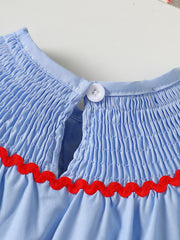 Baby blue smocked top with red ric rac trim and button closure.