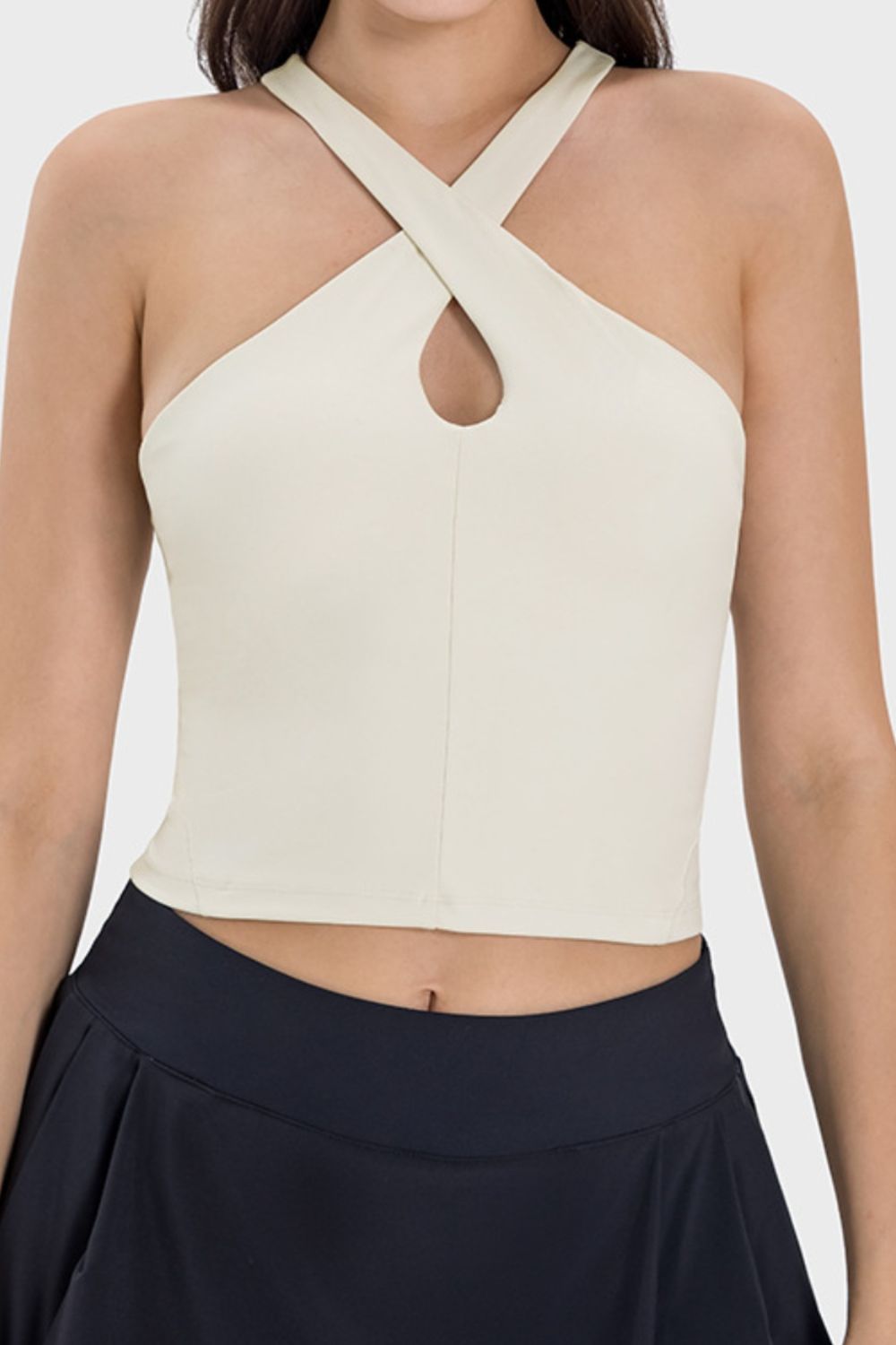 Cream halter crop top with keyhole cutout and crisscross straps.