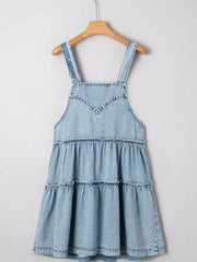 Tiered denim overall dress in light blue with ruffled tiers and V-neck bodice.
